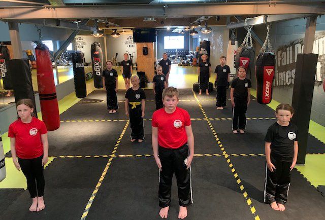 A BKA kids' class standing in rows on the taped mats at South Coast Gym