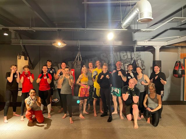 An adults' kickboxing class at BKA lined up in guard in front of the heavy bags